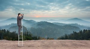 Businessman standing on ladder against scenic countryside with mountains