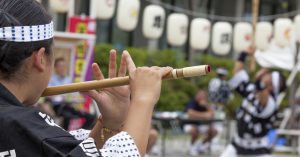 秋田の昼竿灯祭りで篠笛を吹く女性