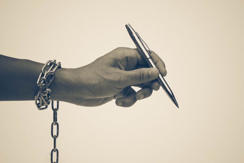 手錠をかけられたペンを持つ手