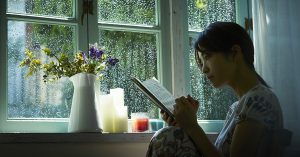 雨の日に室内で本を読む女性