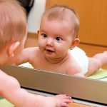 鏡の自分の姿を見つめる男の赤ちゃん
