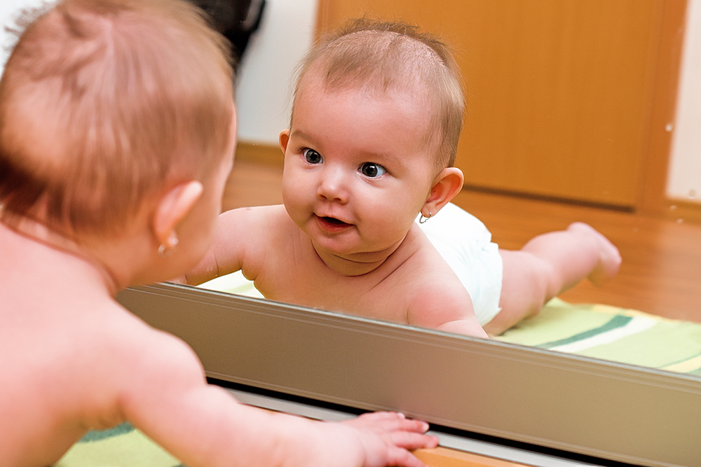 鏡の自分の姿を見つめる男の赤ちゃん