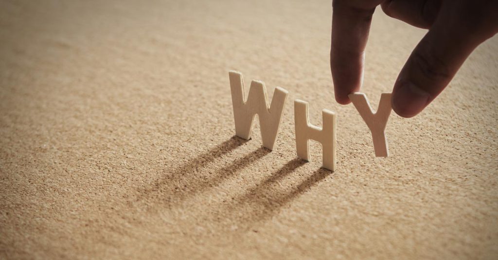 砂の上にWHYというアルファベットを置いている指
