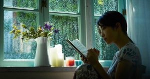 雨の日に窓の前で読書する女性