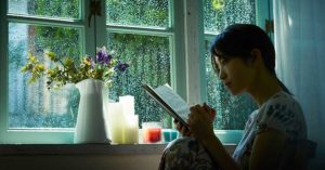 雨の日に窓際で本を読む女性