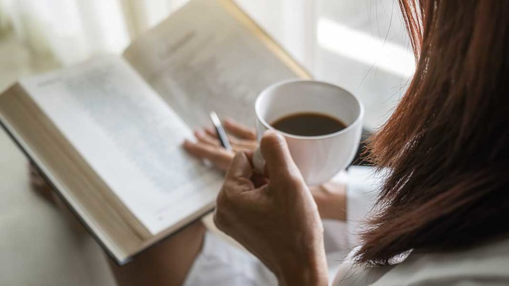 コーヒーを手に読書する女性