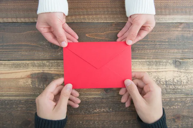 赤い封筒に入った手紙を渡す女性と受け取る男性